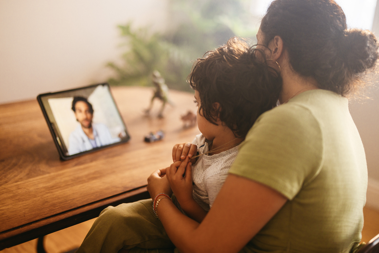 A mother and child speaking with a doctor by video at home